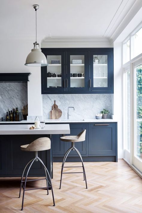 a classic navy kitchen with vintage cabinets, white countertops and a white stone backsplash, vintage pendant lamps