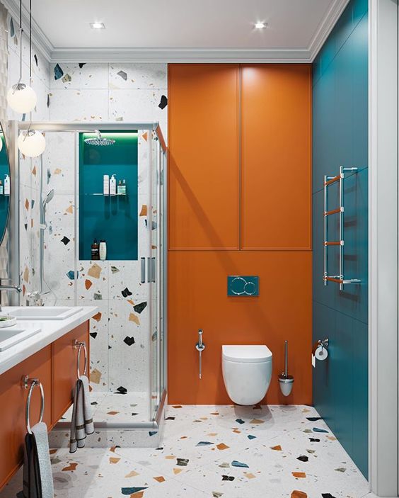 a colorful bathroom with blue and orange touches, terrazzo and white appliances and built-in lights