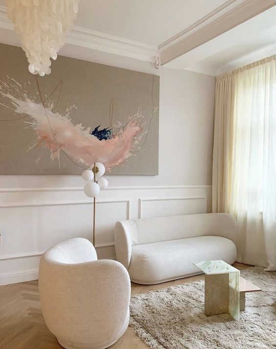 an exquisite living room in neutrals, with a bold abstract artwork, a curved chair and a loveseat, a seashell chandelier