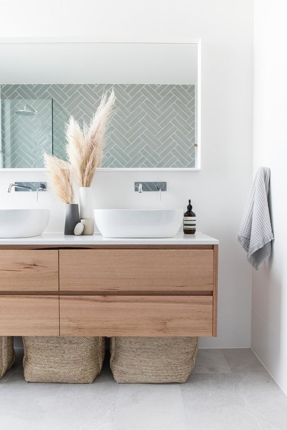 74 a boho bathroom with a sleek wooden floating vanity, baskets for storage, a long mirror and pampas grass in vases