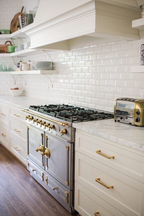 76 a beautiful vintage kitchen in white, with a white subway tile backsplash and gold fixtures for a more elegant feel