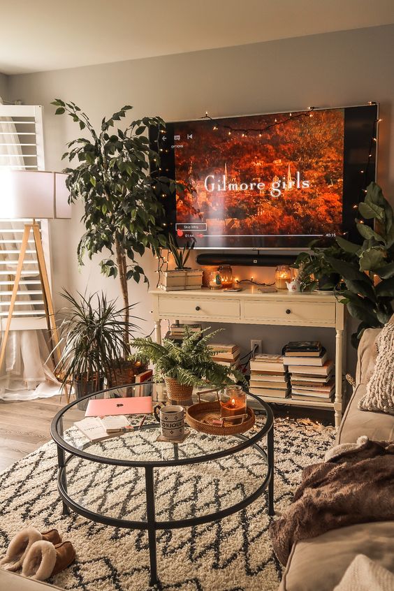 a welcoming modern living room with lots of plants and stacks of books is a very pleasant space to be