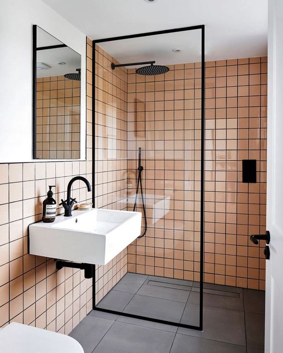 a peachy pink and white bathroom with black fixtures and white appliances is a very chic and pretty space