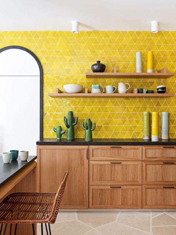 a bold boho kitchen with rich stained cabinets, black countertops, open shelves, a bold yellow tile accent wall