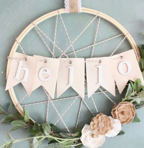 a creative rustic spring wreath with yarn, a HELLO banner, some greenery and fabric blooms is all cool