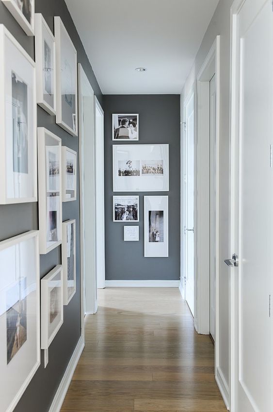 a laconic modern gallery wall with white frames and a free form is a cool way to style an awkward nook in a corridor