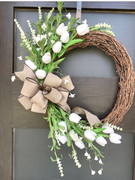 a simple rustic vine wreath with faux white tulips, greenery and a large urlap bow is a beautiful idea