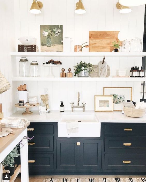 a beautiful black farmhouse kitchen with shaker cabinets, floating shelves, retro sconces and mixed metals for more eye-catchiness