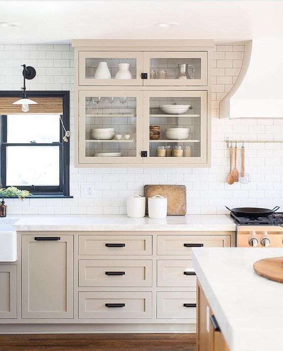 a beautiful light stained shaker style kitchen with a white subway tile backsplash and white quartz countertops plus black fixtures