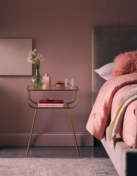 a beautiful mauve bedroom with a lavender bed, pink bedding, a pretty glass nightstand and some accessories