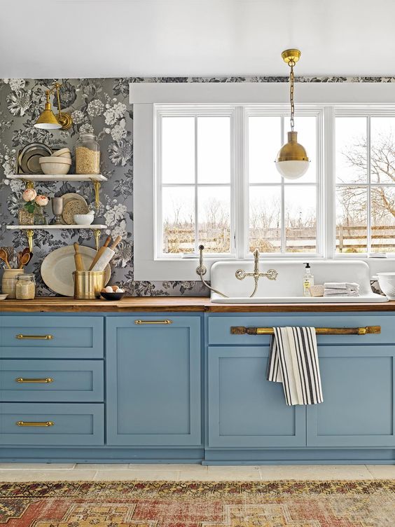 a beautiful one wall blue kitchen with floral wlalpaper, butcherblock countertops and pretty vintage pendant lamps