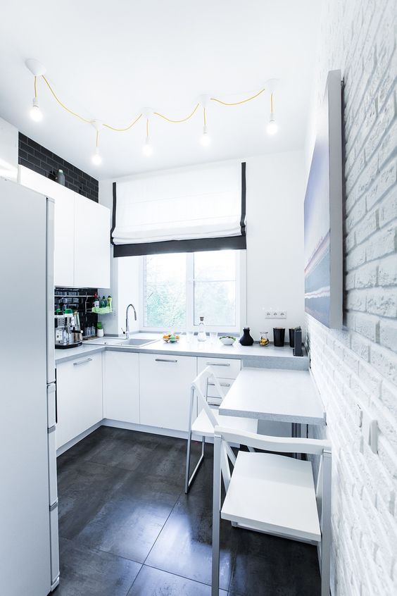 a black and white Scandinavian kitchen with a black backsplash and a small eating zone