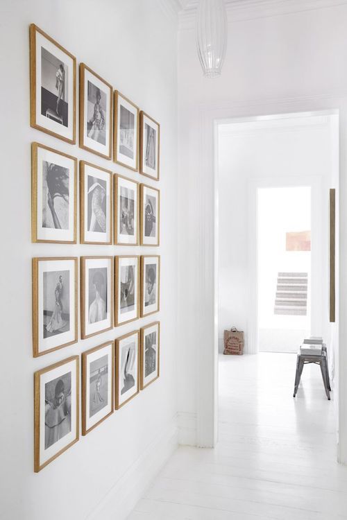 a blank wall filled with a grid gallery wall with stained frames and black and white photos is pure elegance