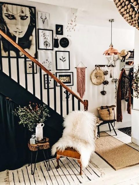 a bold boho gallery wall with mismatching frames, large artworks, macrame hangings in various colors and a mobile hanging