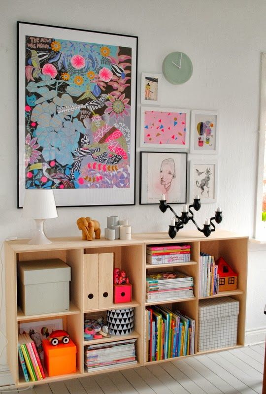 a bold gallery wall with bright posters and watercolors in black and white frames to give more color to the space