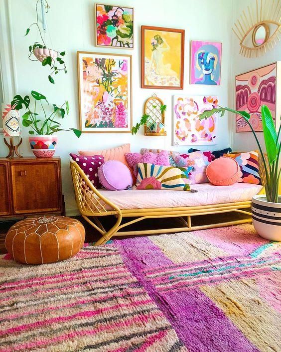 a bright and colorful gallery wall with mismatching frames, bold floral and naive artworks and greenery is a cool idea for a boho space