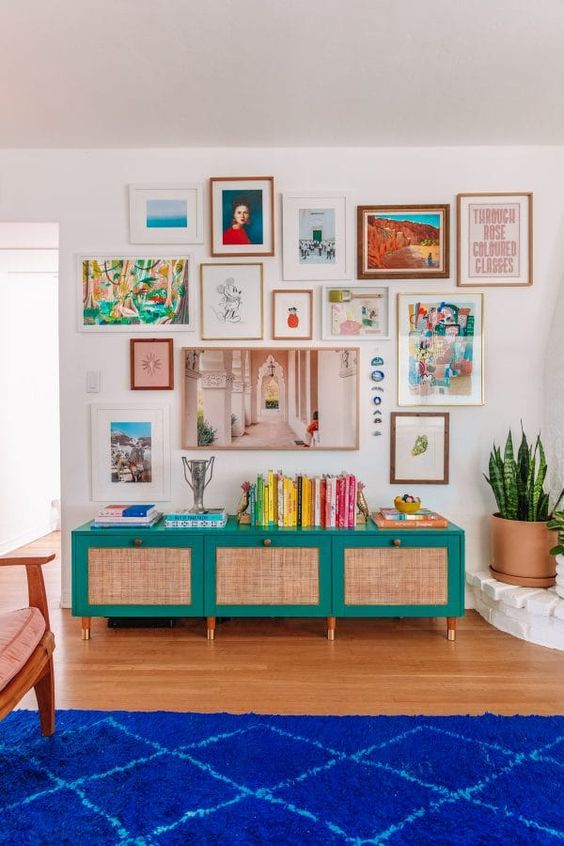 a bright gallery wall with mismatching frames and bold artworks, with a free form and a hanging with blue stones