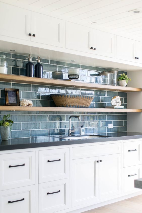 a chic kitchen with white cabinetry, open shelves, a blue tile backsplash is a chic farmhouse space with a touch of coastal decor