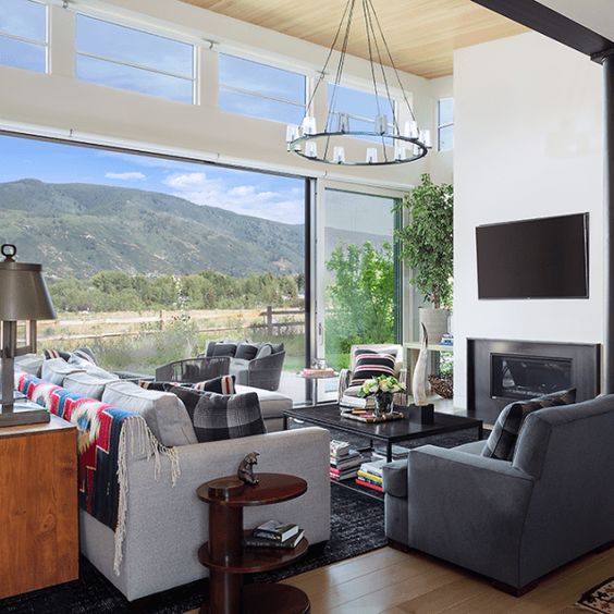 a chic modern living room with comfy furniture and a built-in fireplace, a glazed wall and additional clerestory windows to fill the space with light