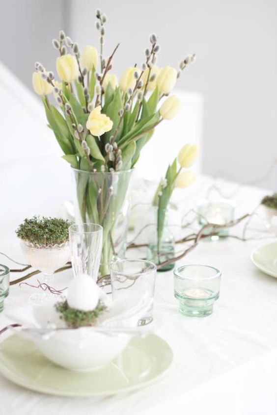 a clear vase with yellow tulips and willow, some branches and grass in a bowl is a lovely spring centerpiece to rock