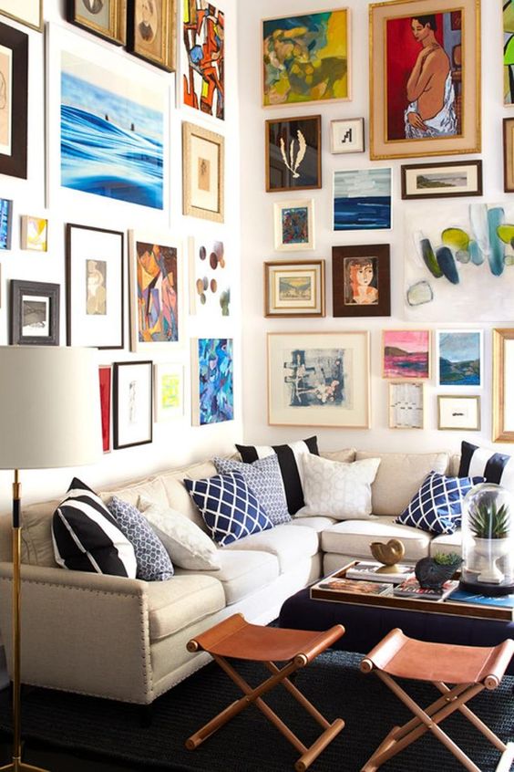 a colorful gallery wall taking two walls with mismatching frames and super bold artworks in various styles and in various colors