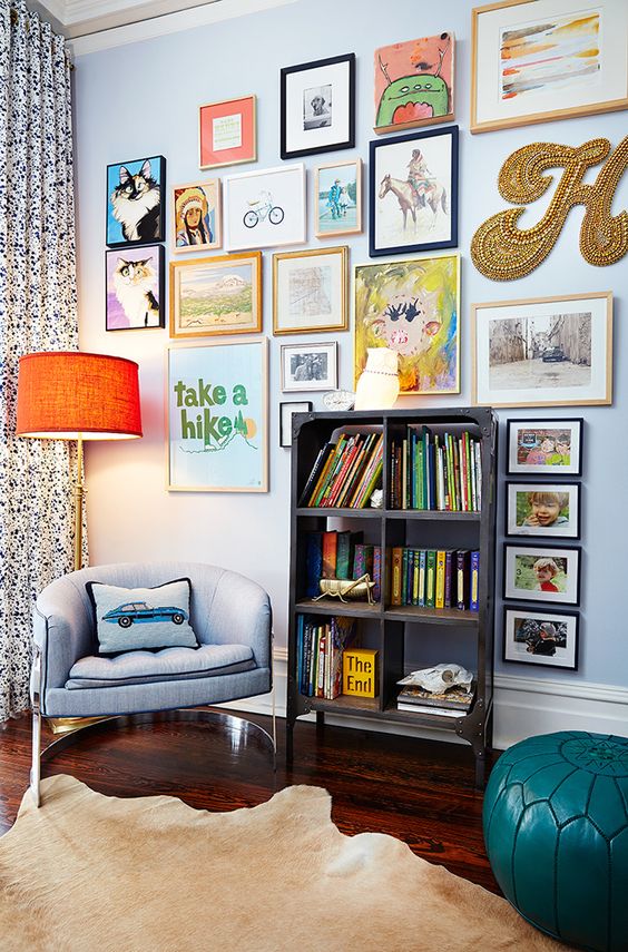 a colorful gallery wlal with mismatching frames, a creative form, a gold bead monogram and some posters is fun