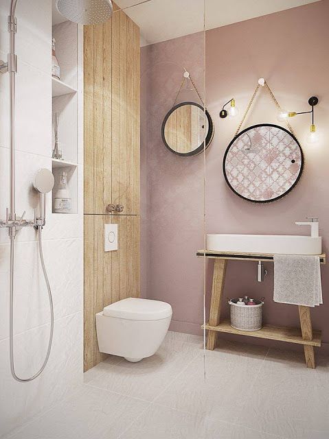 a contemporary bathroom with a mauve wall, wooden touches, round mirrors and a shower space