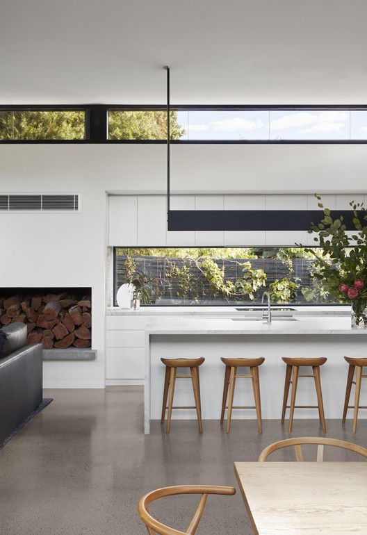 a contemporary white space with a long window as a backsplash and clerestory windows plus contemporary furniture