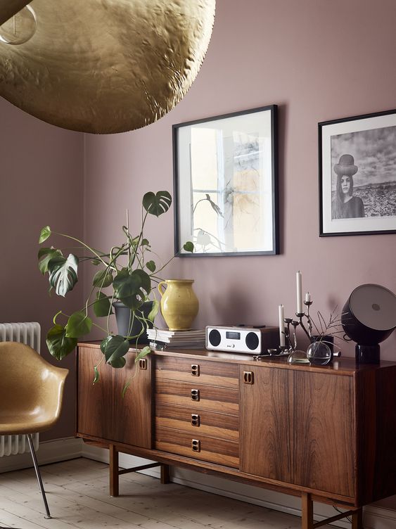 a cool mid-century modern living room with mauve walls, chic furniture, statement artworks and touches of gold