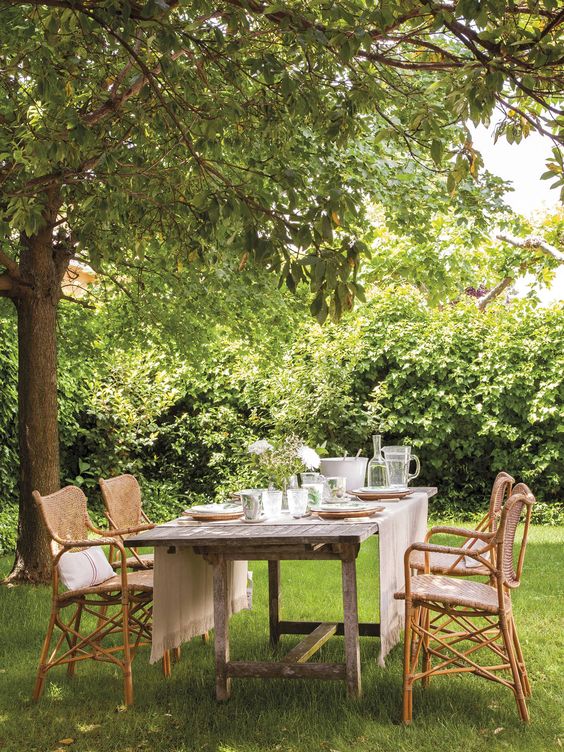 a cool rustic dining area with a reclaimed wooden table and rattan chairs and neutral linens is very chic