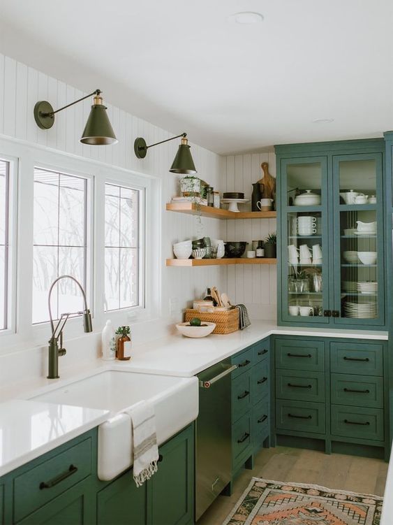 a green farmhouse kitchen with a glass cabinet, white stone countertops and black handles is a chic space