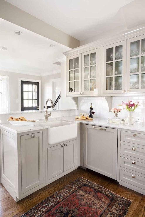 a grey L-shaped farmhouse kitchen with brass knobs and white stone coutnertops looks very elegant and stylish