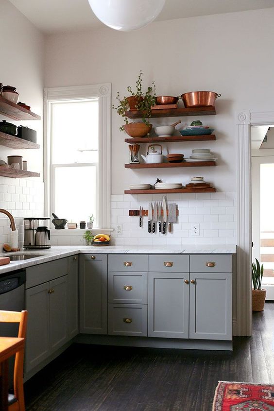 a grey boho L-shaped kitchen with open shelves, a white stone countertop and a white tile backsplash plus greenery