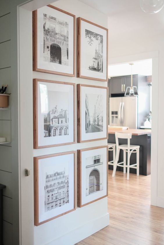a grid gallery wall with stained frames and black and white photos is a stylish way to spruce up your space