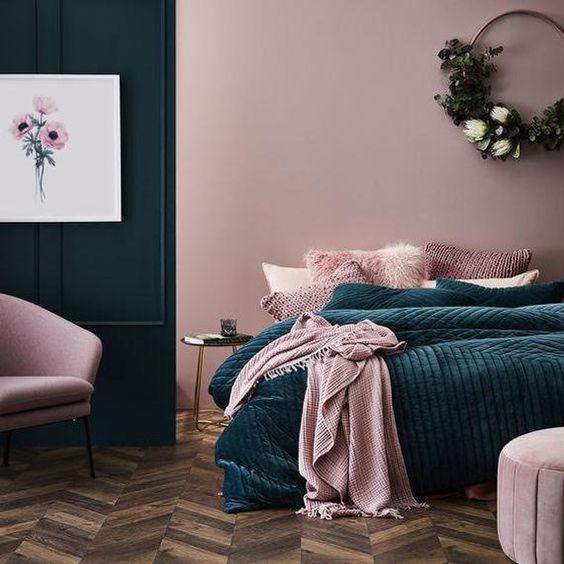 a mauve bedroom with a statement teal wall, teal and pink bedding, pink and mauve furniture and a wreath