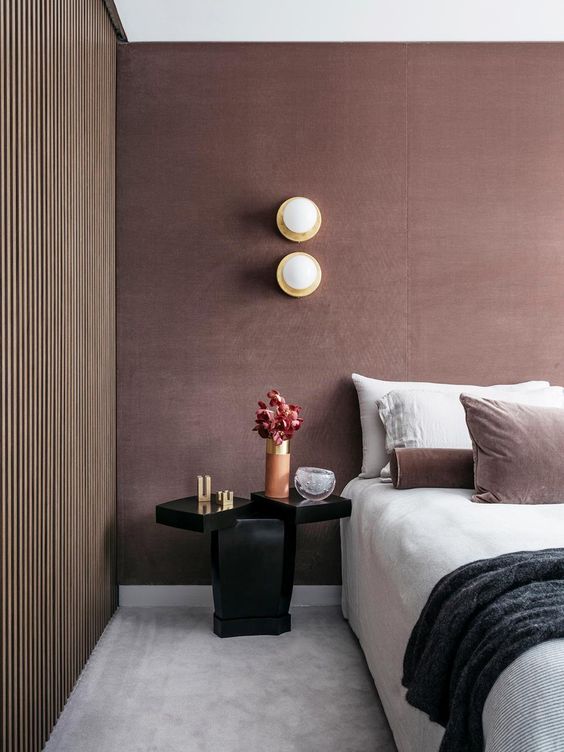 a mauve bedroom with a white bed, a black refined nightstand, chic bedding plus gold touches