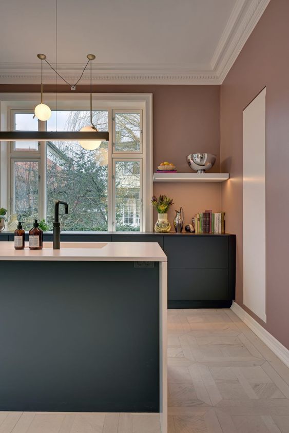 a mauve kitchen with graphite grey cabinets, white and black countertops, pendant lamps and a large window