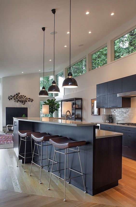 a mid-century modern kitchen with black cabinetry, clerestory windows for more light, pendant lamps and leather chairs