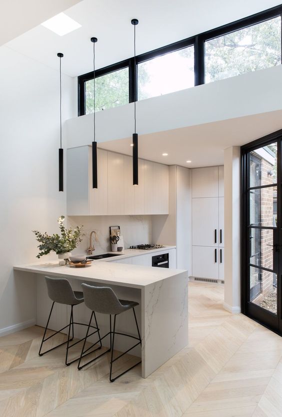 a minimalist space in black and white, with minimalist furniture and black pendant lamps plus a clerestory window over the space