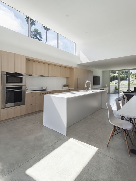 a minimalist space with a kitchen and dining room, with minimal furniture, a glazed wall and a clerestory window for more light here