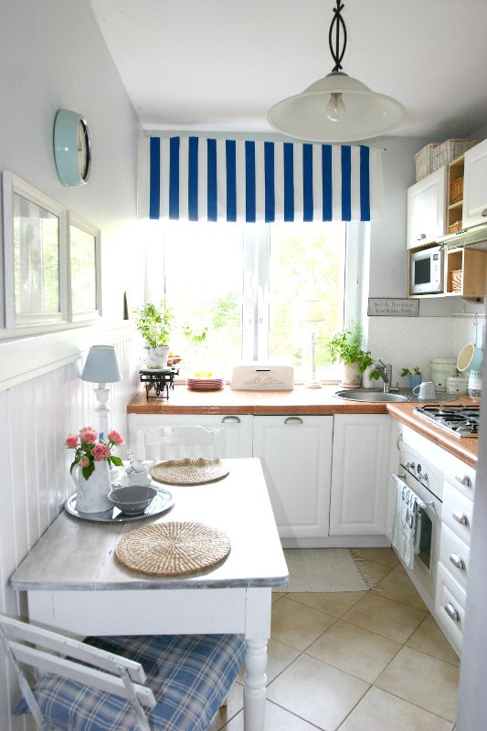 a modern coastal L-shaped kitchen with rich-stained butcherblock countertops, printed blue textiles and potted greenery