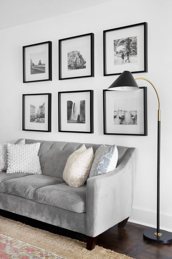a modern living room with a grid gallery wall, a grey sofa with printed pillows and a black floor lamp
