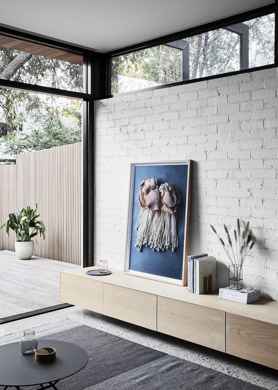 a modern living room with a white brick wall, a glazed wall and clerestory windows that fill the space with more light