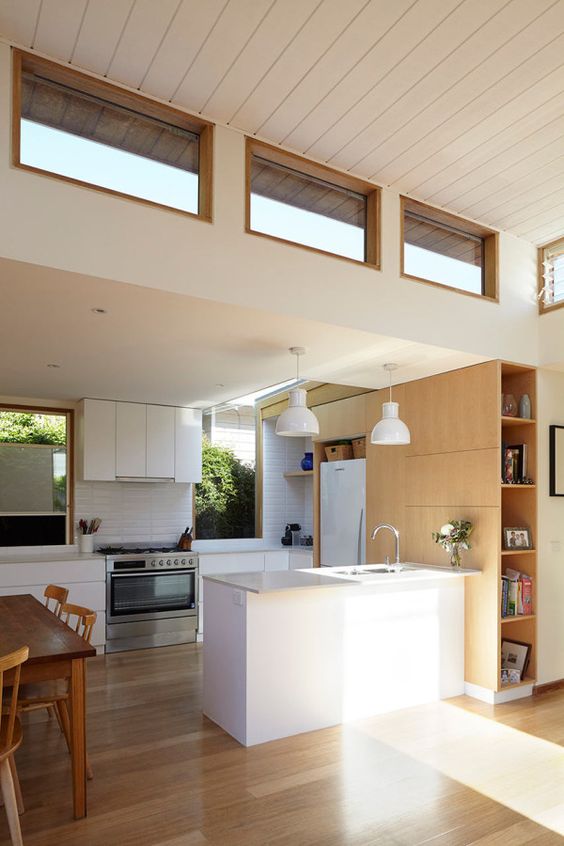 a modern neutral space with white and blonde wood furniture, usual and clerestory windows for more light inside