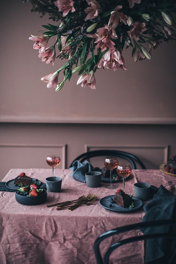 a moody mauve dining room with black chairs, mauve and black linens and plates is a very refined idea