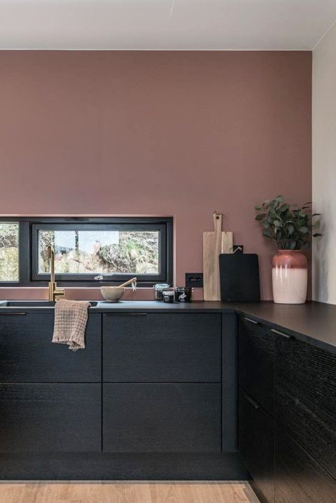 a moody mauve kitchen with lower black cabinets, a window backsplash and various neutral and black accessories