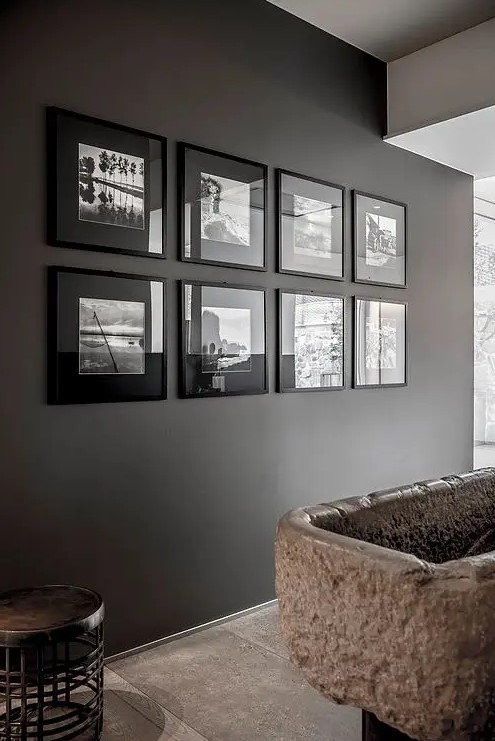 a moody symmetrical black and white gallery wall with matching black frames and black and white pics for a moody space