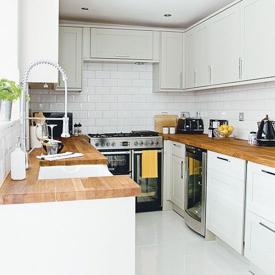 a neutral U shaped kitchen with butcherblock countertops and stainless steel appliances is stylish