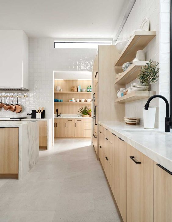a neutral contemporary kitchen with blonde wood cabinets, white tiles and stone countertops and a clerestory window