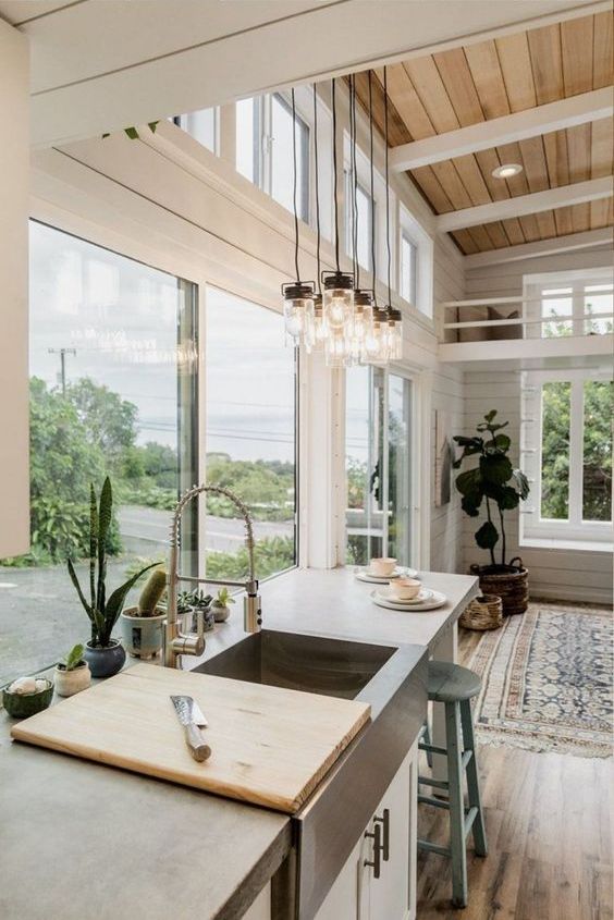 a neutral farmhouse kitchen done with beadboard, a glazed wall and additional clerestory windows plus potted plants